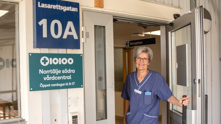 Sjuksköterska öppnar entrédörren till vårdcentral. 