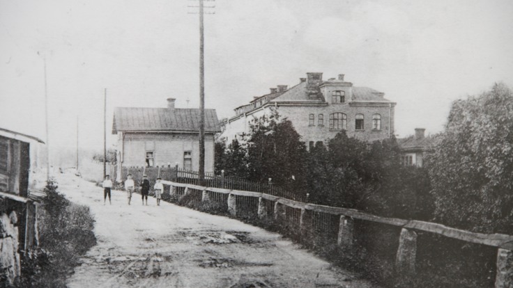 Historisk bild, grusväg med tegelbyggnad i bakgrunden