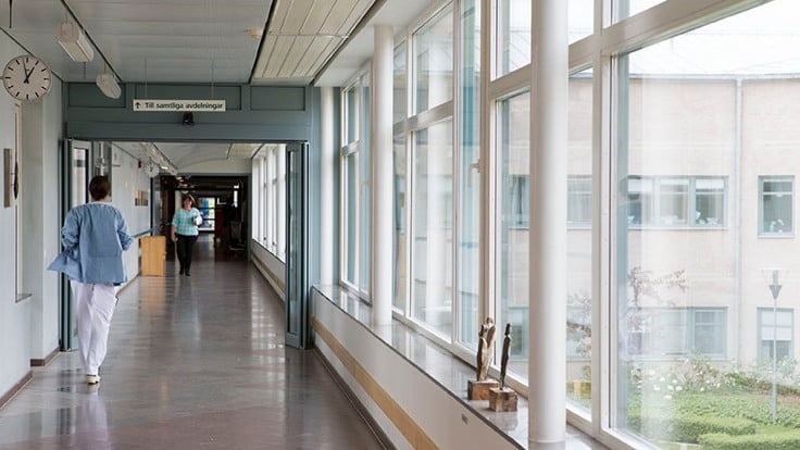 Person i sjukhuskläder går i korridor på sjukhus.