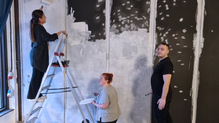 Tre personer målar en vägg.