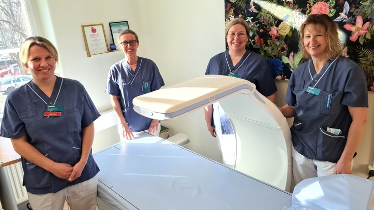 Kvinnor i sjukvårdskläder samlade runt brits med röntgenutrustning
