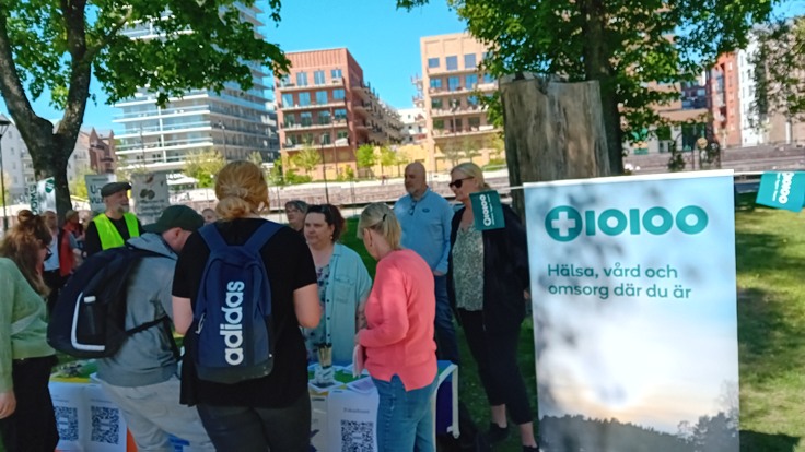 Invånare står vid Tiohundras bord. Bredvid bordet står en rollup med tiohundras logotyp och texten 