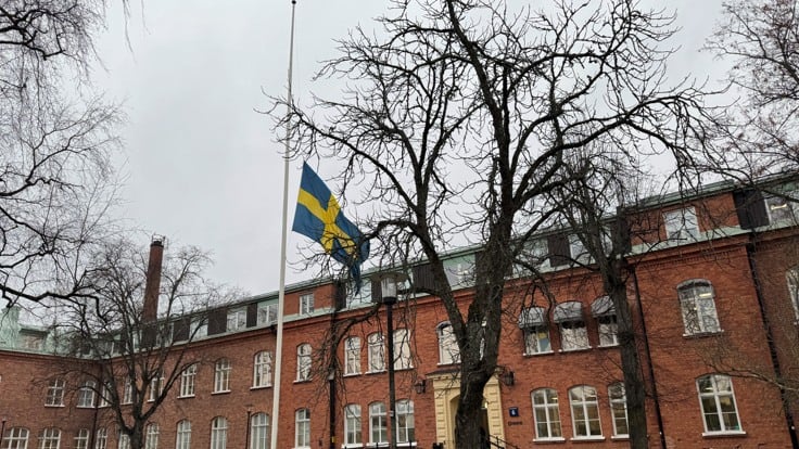 Flagga på halv stång framför tegelbyggnad