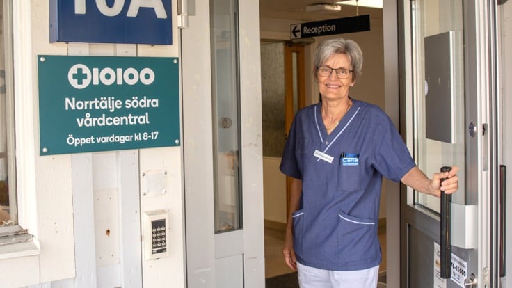 Sjuksköterska öppnar entrédörren till vårdcentral. 