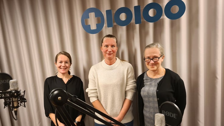 Tre kvinnor i studio med mickar i förgrunden. I bakgrunden syns en logga med texten 10100.