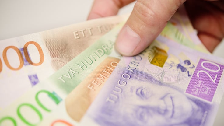 Hand som håller i svenska sedlar i olika valörer