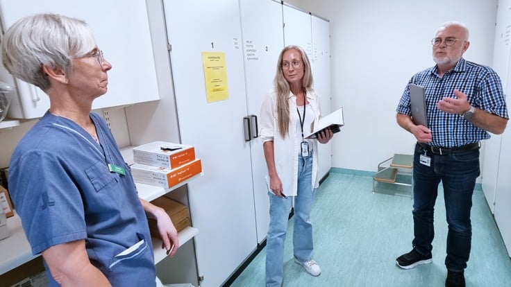 En man och två kvinnor i ljus förrådslokal på sjukhus. 