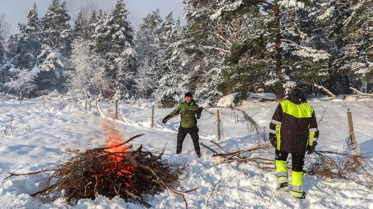 Två män som eldar ris ute i snön